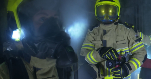 Firefighters in reflective helmets and uniforms with a hose